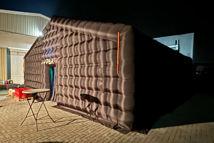 Opblaastent als tijdelijke eventlocatie bij een bedrijfspand in de avond.