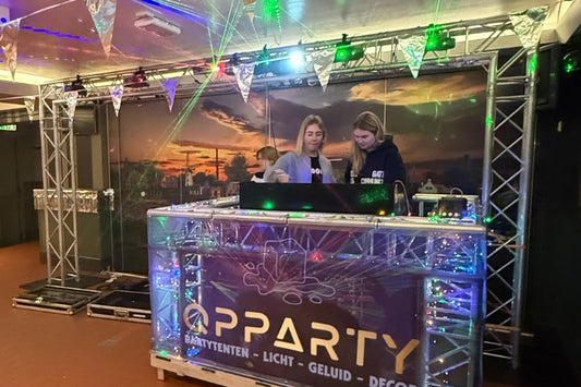 DJ-opstelling met truss, verlichting en geluidsinstallatie tijdens een evenement.