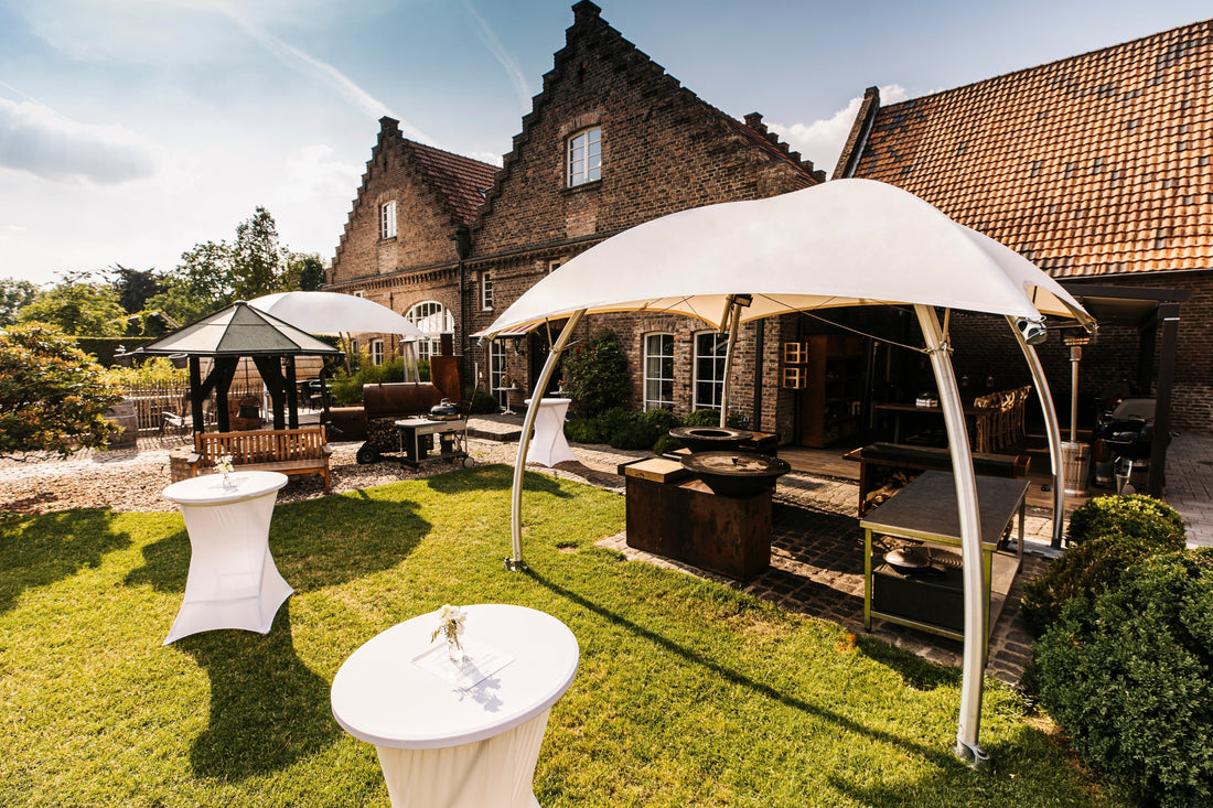 Witte Lounger tenten in een sfeervolle tuinopstelling bij een landhuis, met loungezitjes en statafels tijdens een buitenevent.