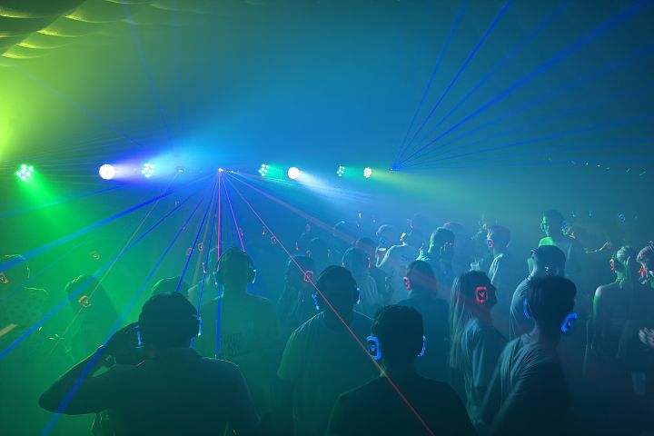 Feestende mensen op een dansvloer met groene en blauwe verlichting en lasereffecten