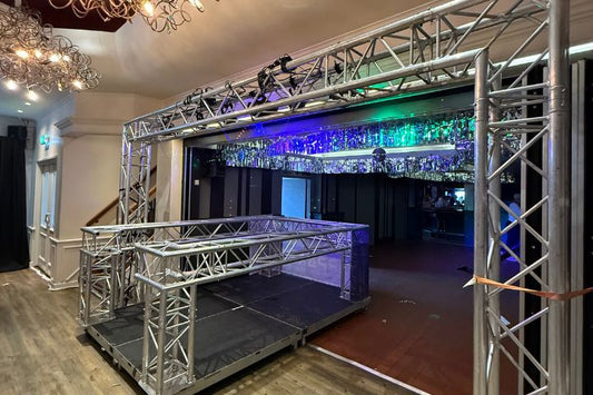 Aluminium trussconstructie met DJ-booth en gekleurde verlichting in een evenementen locatie