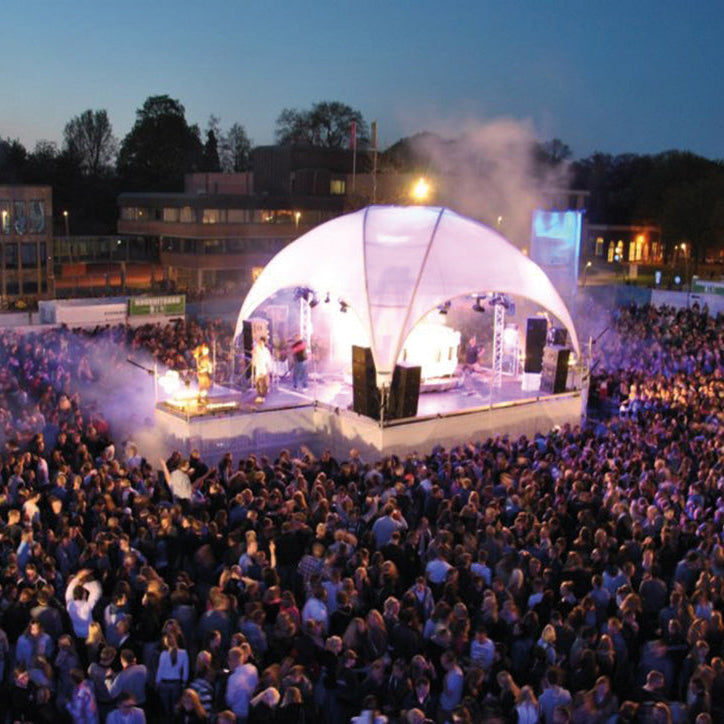 Avondfoto van een groot festival met een Qpparty Crossover stage, compleet met verlichting, rook en een volle menigte rondom het podium.