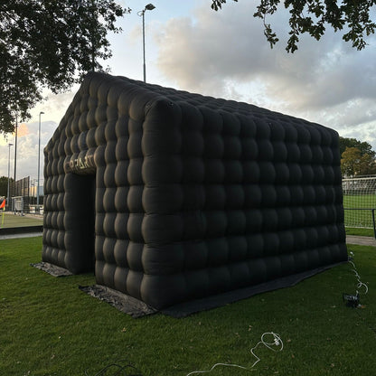 Zijaanzicht van een grote zwarte opblaastent van Qpparty, opgesteld op een grasveld, met afmetingen van 3,5 meter hoog, 5,5 meter lang en 4,8 meter breed. Met een capaciteit van 40 tot 50 man.
