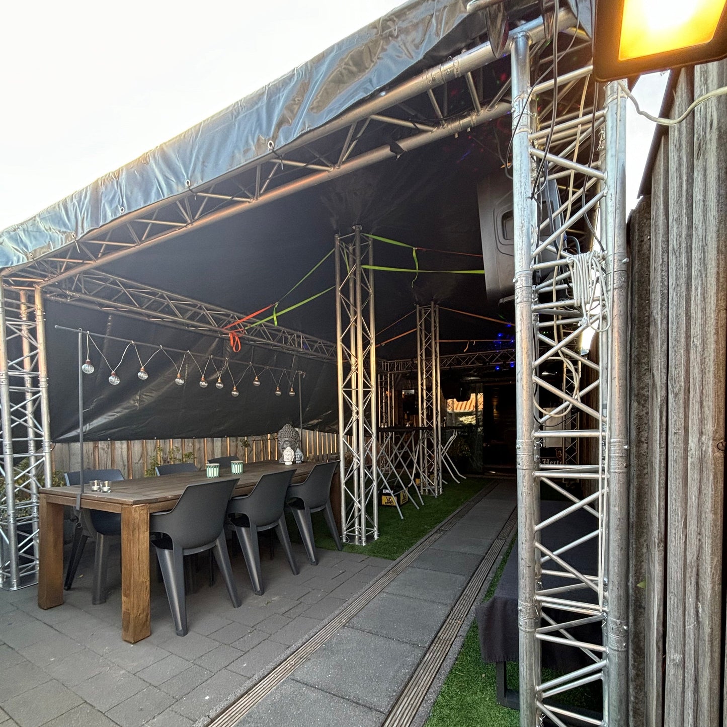 Foto van een QPparty truss tent van 3 meter breed, 6 meter lang en 2,3 meter hoog, met afdekzeilen, schuindak, geïntegreerde trussconstructie, verlichting en speakers. De tent is volledig aanpasbaar.