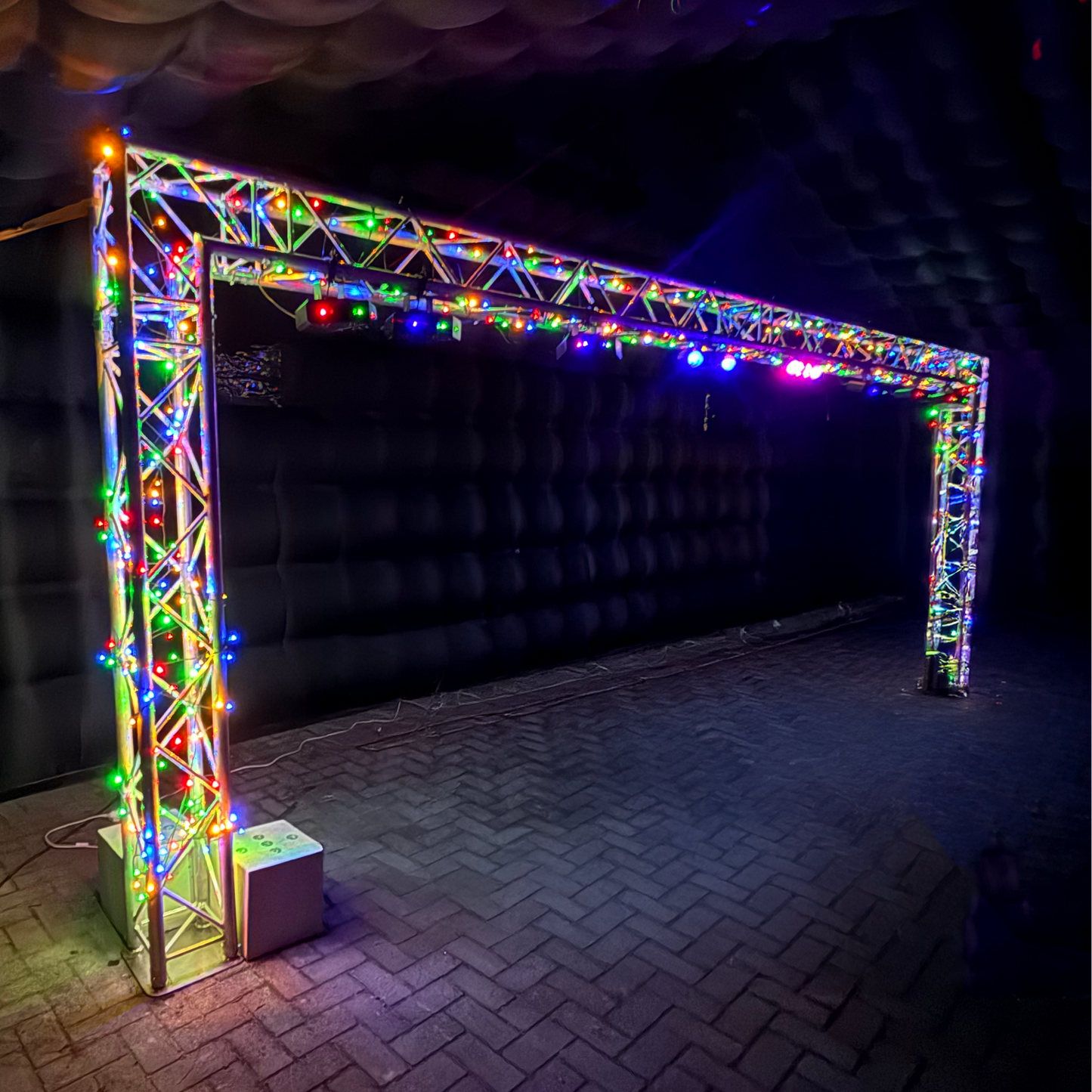 Foto van een verlichte trussboog van QPparty, 2,3 meter hoog en 6,6 meter breed, opgebouwd met gekleurde LED-verlichting in een opblaasbare partytent
