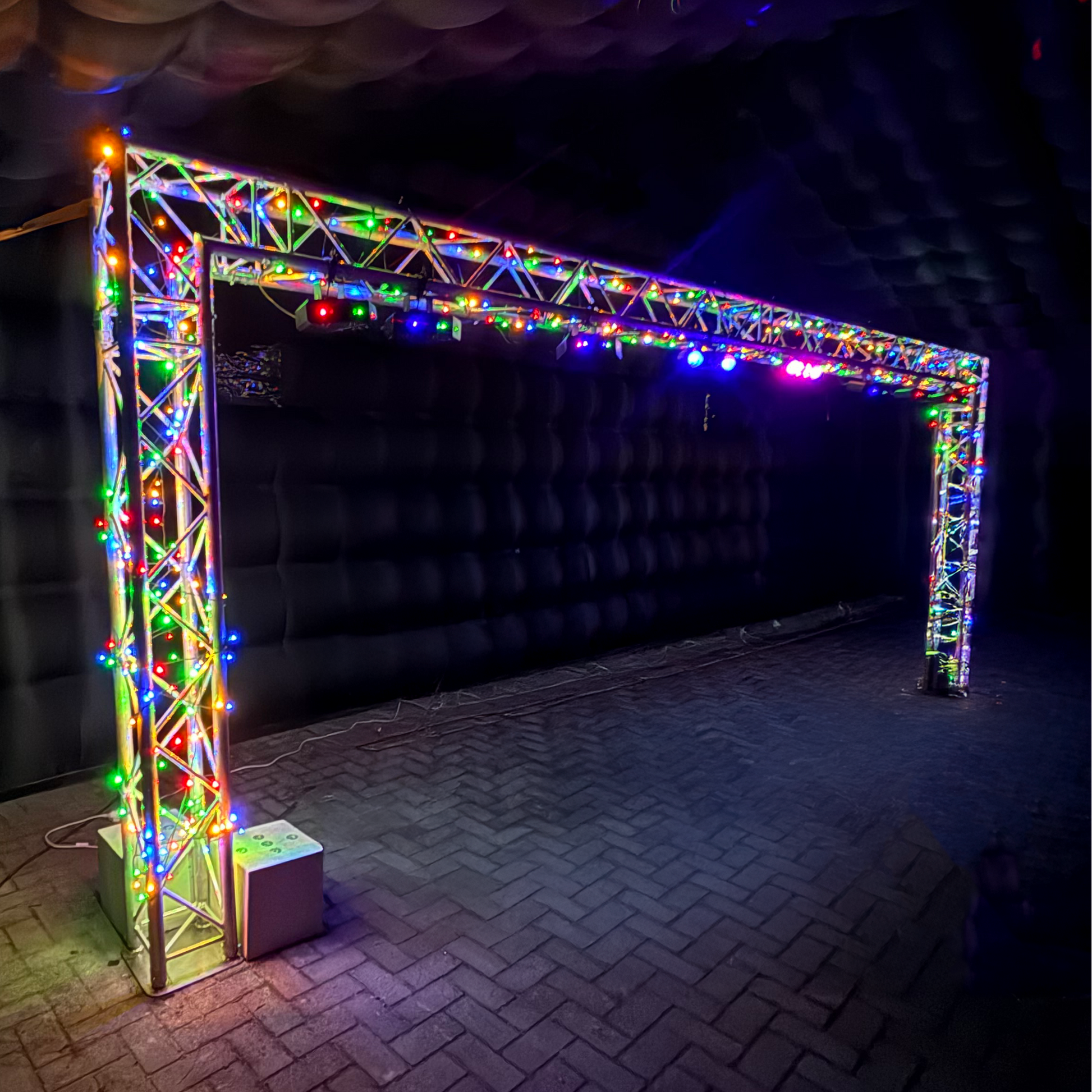Foto van een verlichte trussboog van QPparty, 2,3 meter hoog en 6,6 meter breed, opgebouwd met gekleurde LED-verlichting in een opblaasbare partytent