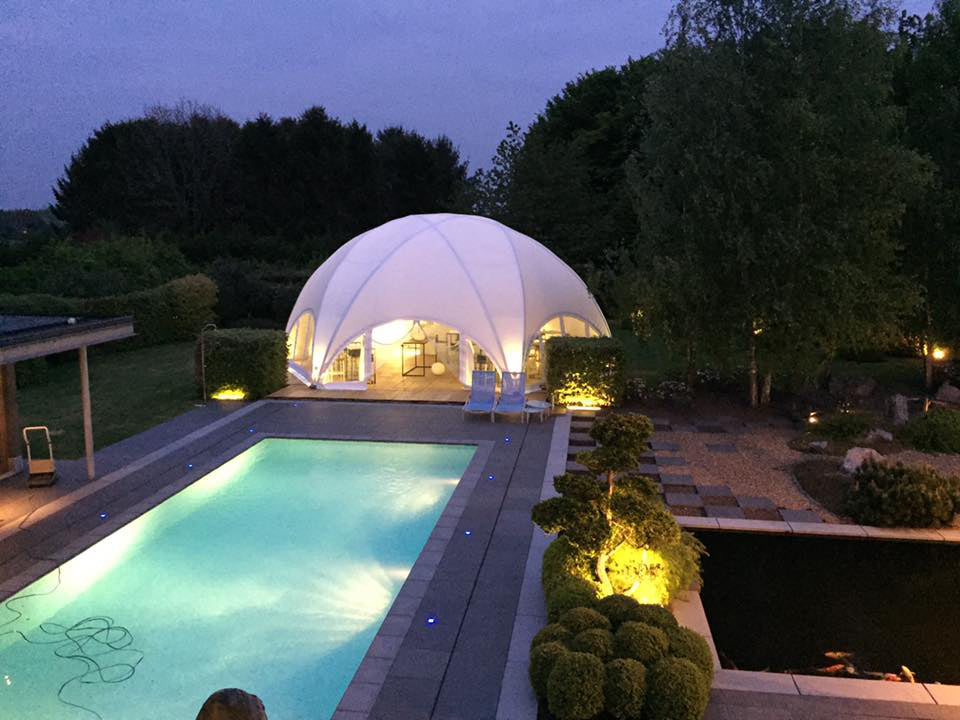 Witte Hexadome eventtent die volledig dicht is bij een zwembad in de avond