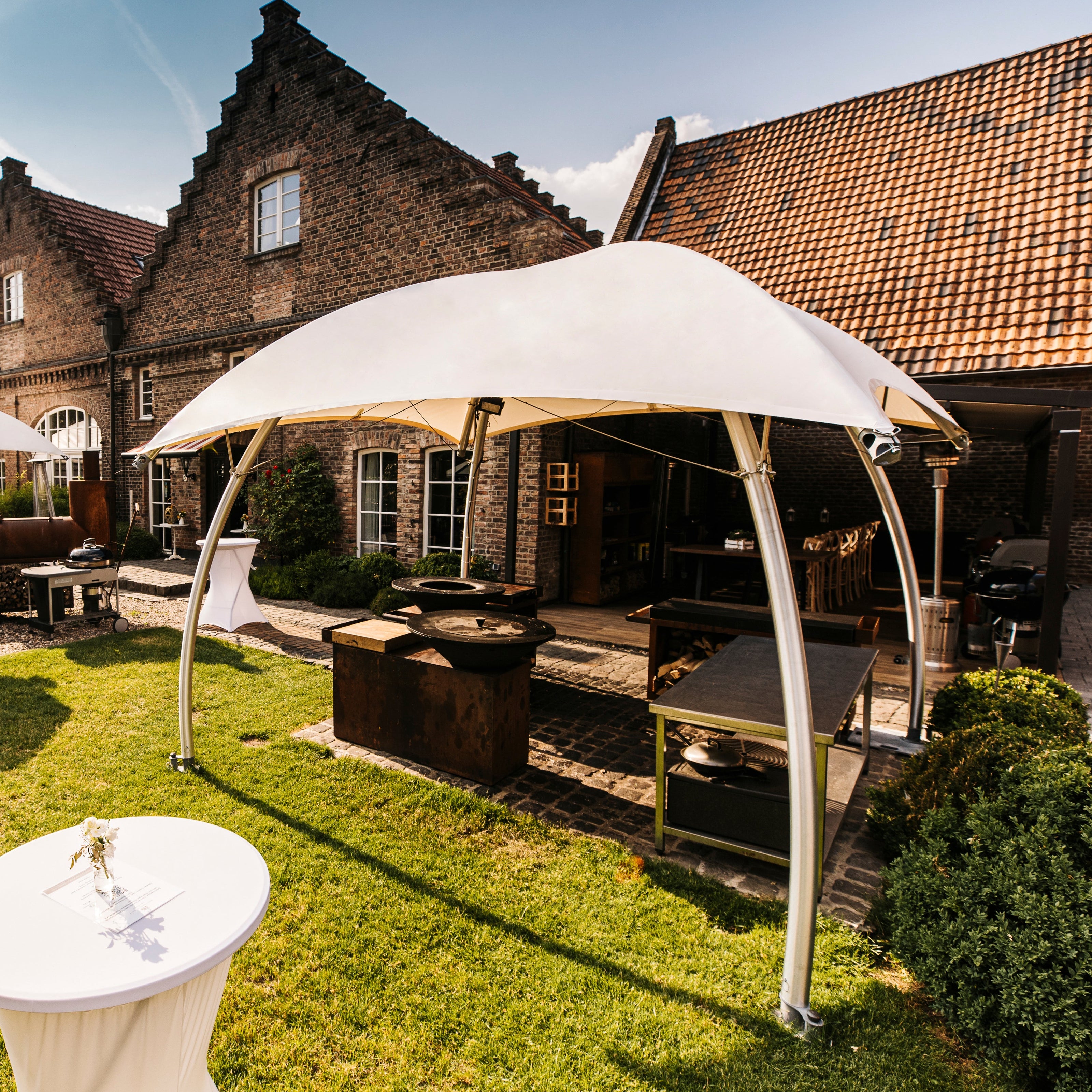 Lounger L met robuust aluminium frame en brandwerende B1-M2 cover, geplaatst op een hoteltuin-terras tijdens een zakelijk buitenevenement.