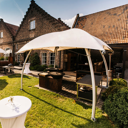 Lounger L met robuust aluminium frame en brandwerende B1-M2 cover, geplaatst op een hoteltuin-terras tijdens een zakelijk buitenevenement.