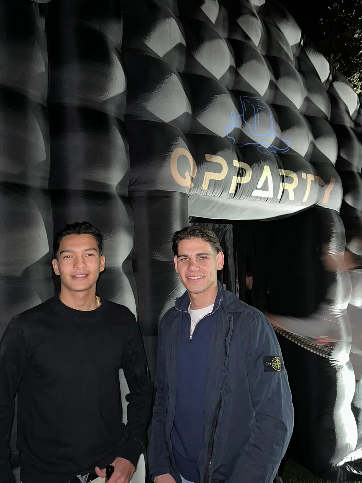 Qpparty werknemers bij een opblaasbare eventtent in de avond