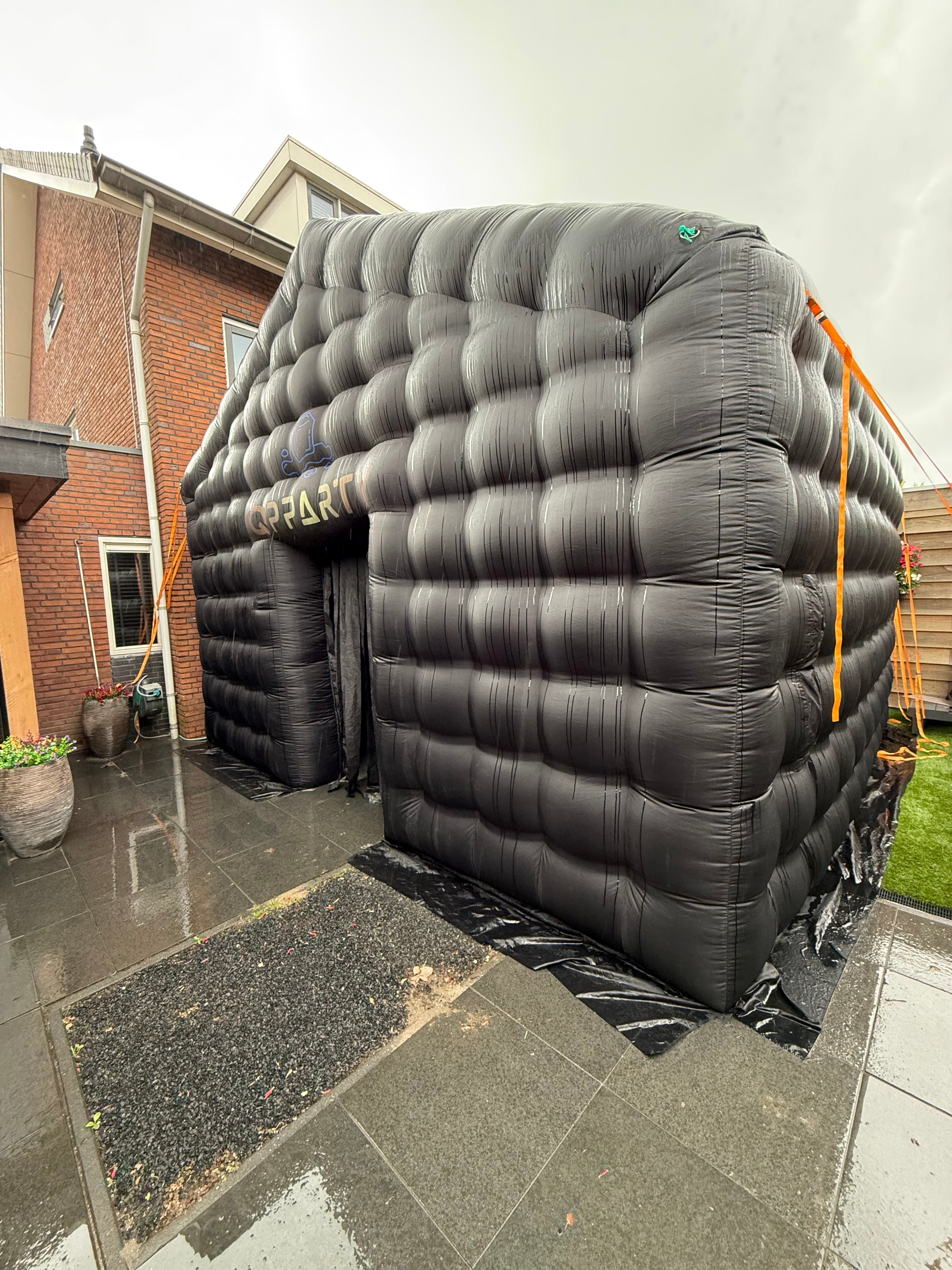 Zwarte grote opblaasbare tent van Qpparty bij een woning