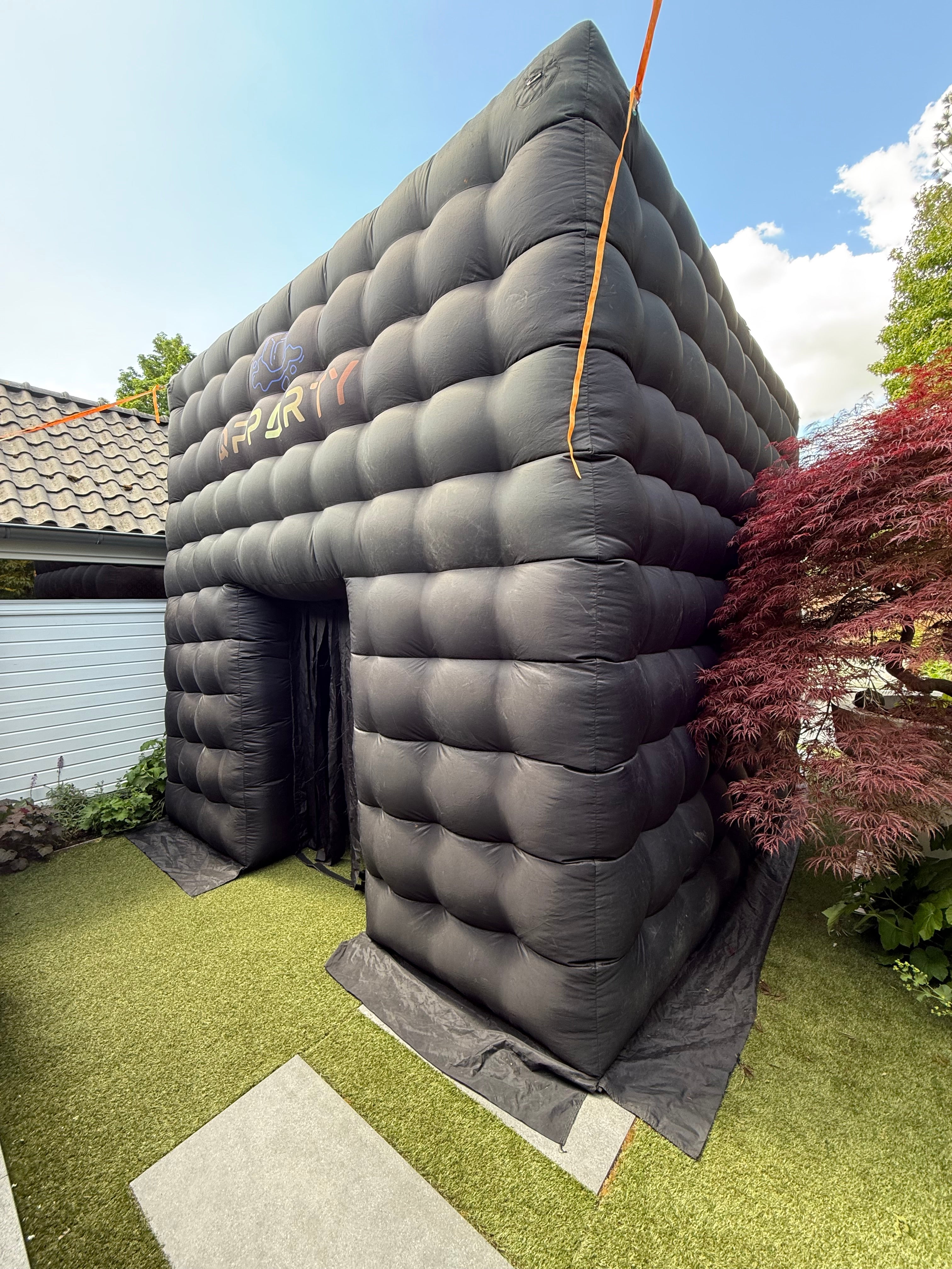 Kleine zwarte opblaasbare tent van Qpparty opgesteld in een tuin