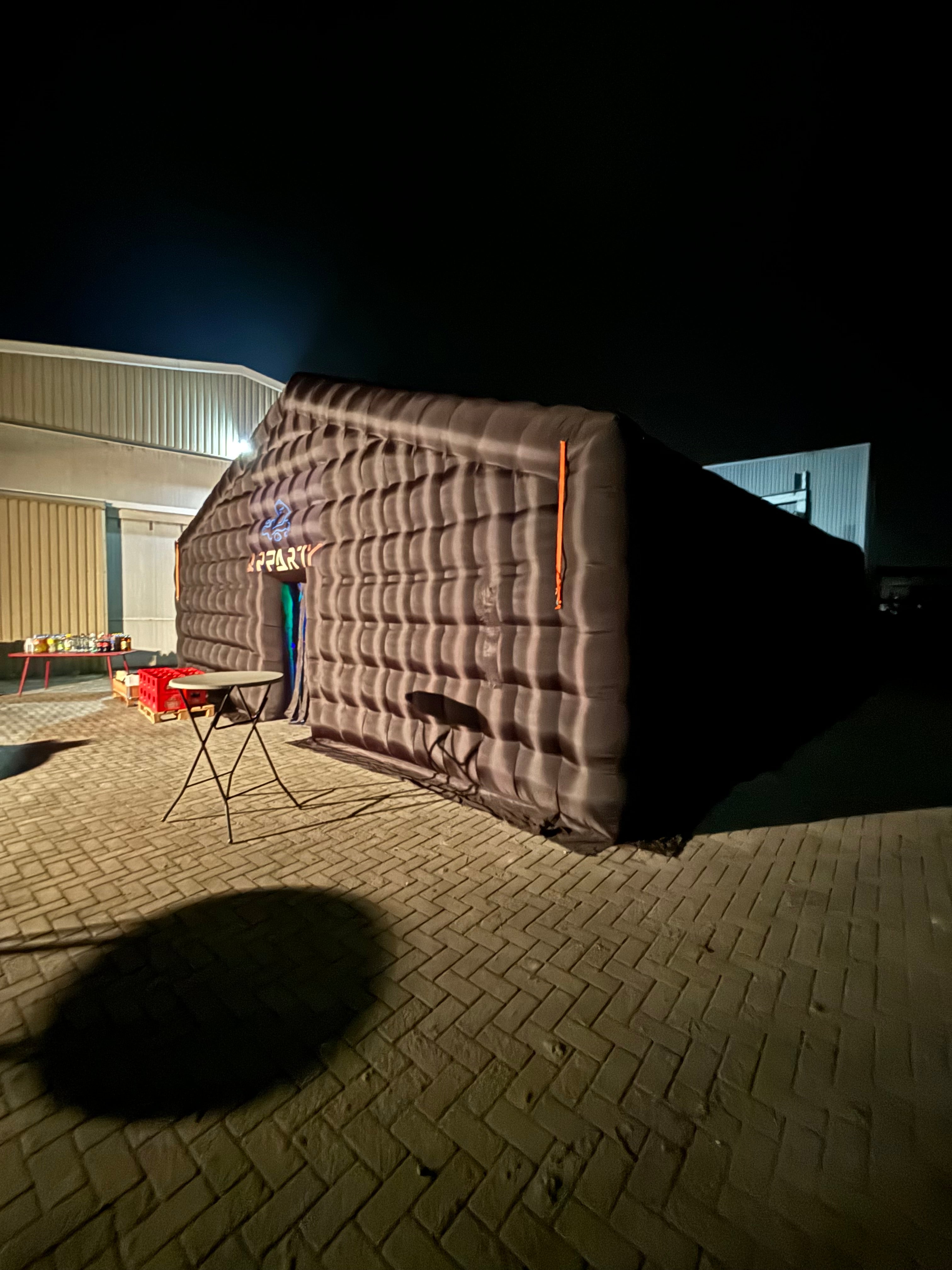 Zwarte opblaasbare tent van Qpparty op een bedrijventerrein in de avond