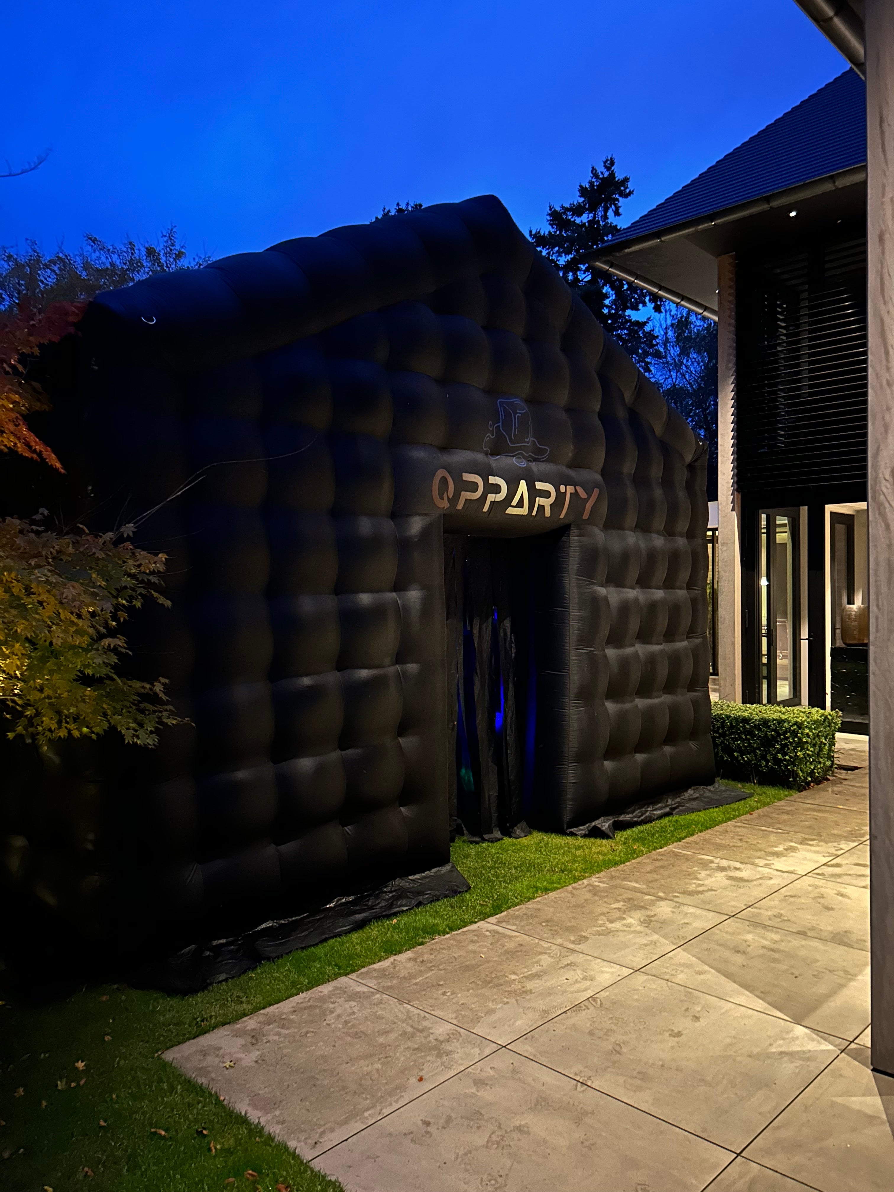 Zwarte opblaasbare tent van Qpparty buiten in de avond