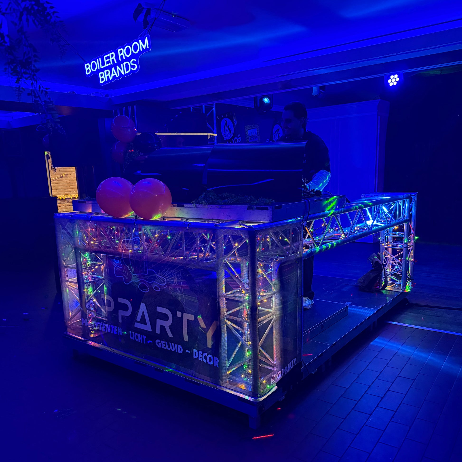 Truss DJ-opstelling met verlichting tijdens een evenement van Qpparty