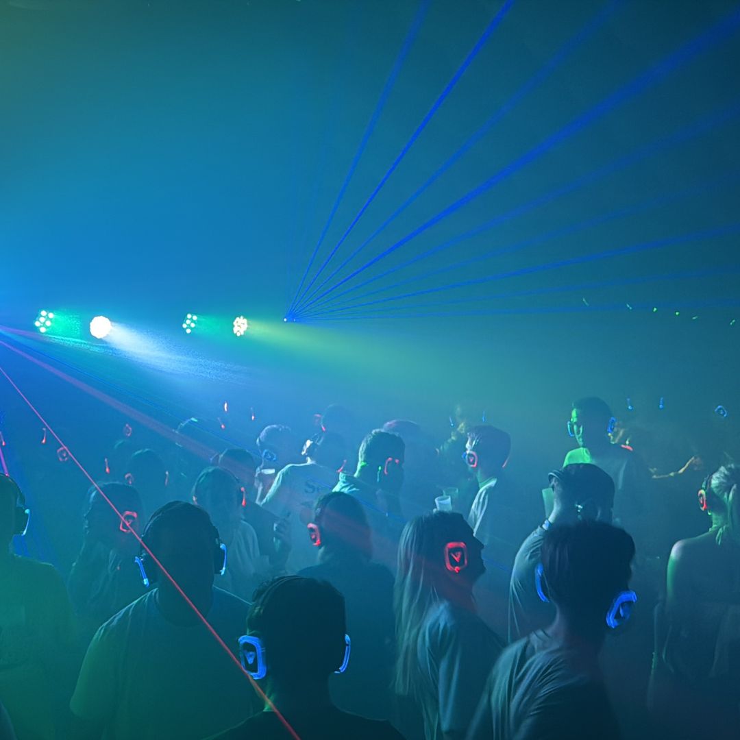 Bezoekers met koptelefoons tijdens een silent disco met licht en lasers