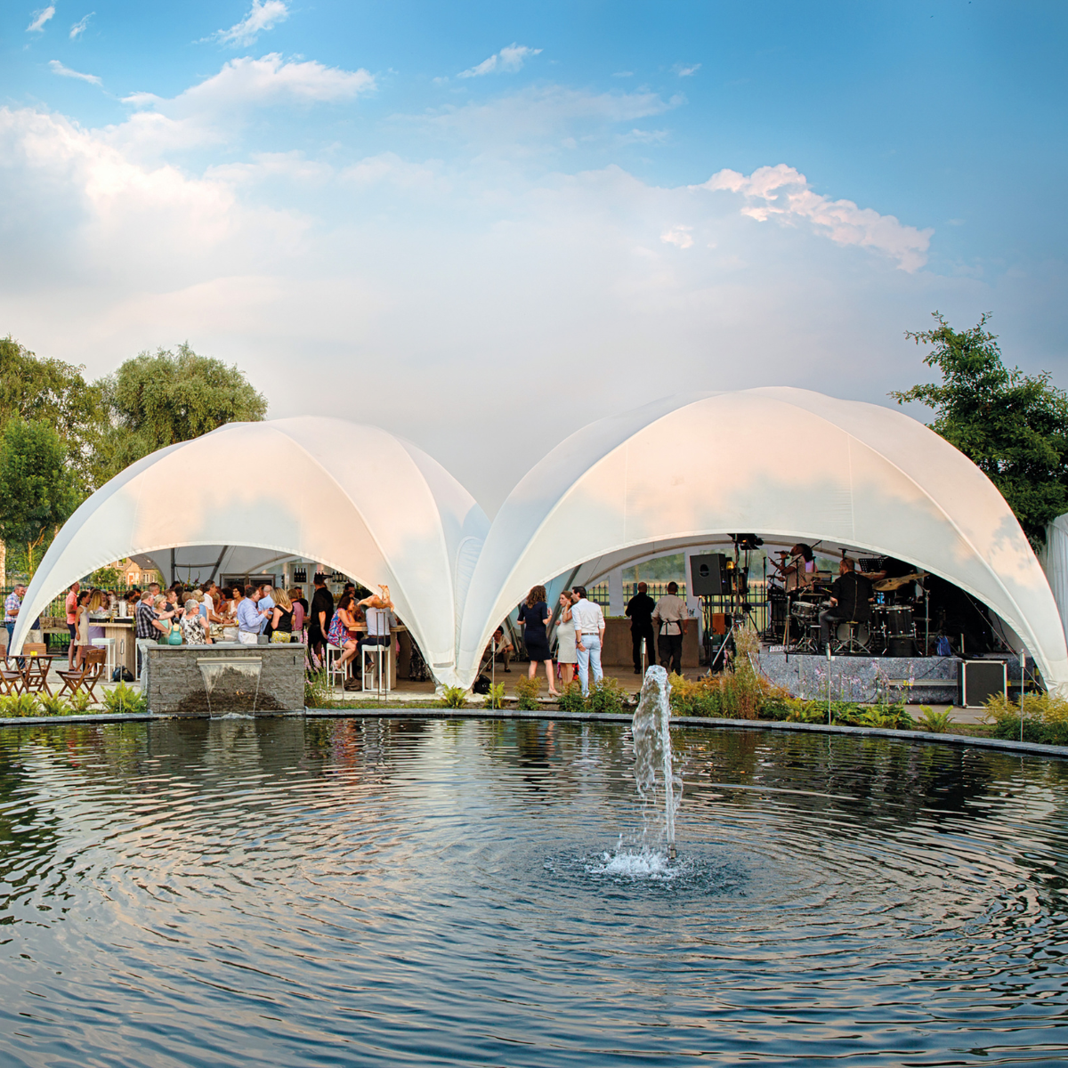 Witte Crossover eventtenten gekoppeld aan elkaar bij een buiten evenement aan het water